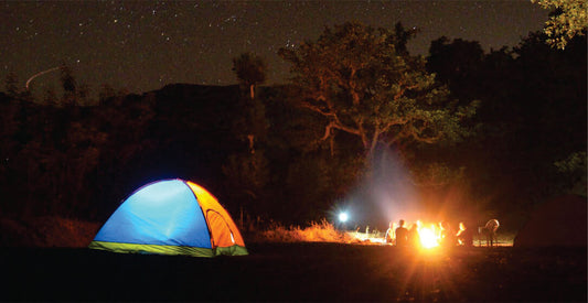 Camping scene with a colorful tent, bonfire, and people around on night safari game drives in Masai Mara.