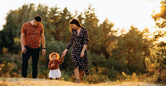Family of three walking together in a natural setting with trees and sunlight on a family safari game drive.