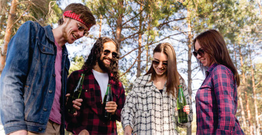 Four friends standing in a forest, holding bottles, with a casual and relaxed atmosphere on group joining safari game drives in Masai Mara