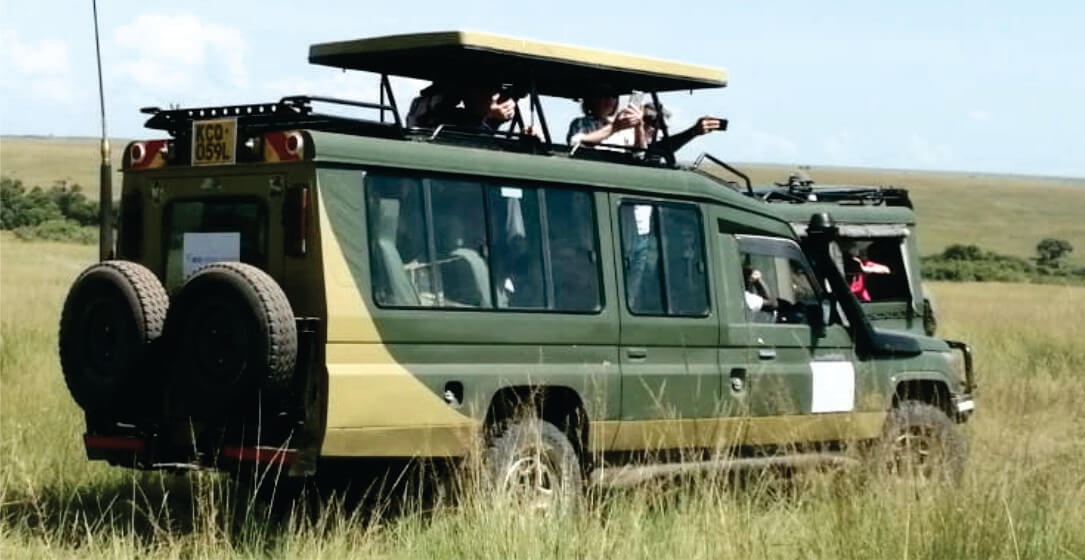Land Cruiser safari vehicle with tourists on a grassy plain 4x4 Mara safari vehicle rental for game drives