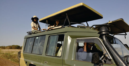 Green safari vehicle with people on a clear day