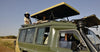 Green safari vehicle with people on a clear day