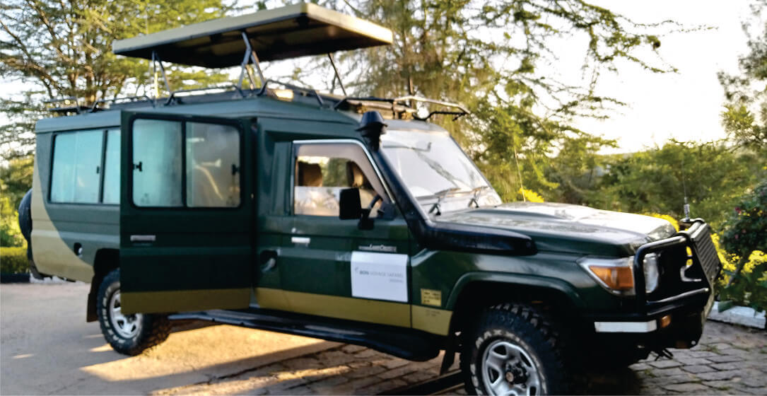 Green safari vehicle hire for Kenya game drives with an open roof on a road, parked near trees