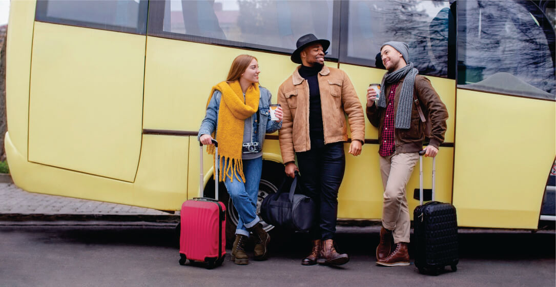 Three people with luggage standing in front of a yellow transfer bus on affordable group transfer from Nairobi to Masai Mara
