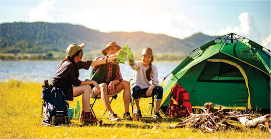 Three people camping outdoors with a green tent and mountains in the background on Masai Mara camping safari game drives