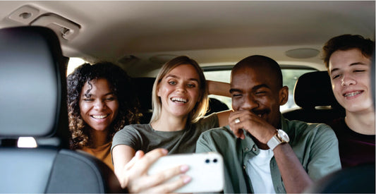 Four friends in a car taking a selfie together.