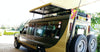 People sitting inside Masai Mara Kenya safari vehicle for hire with large wheels and roof top on a paved road in Kenya