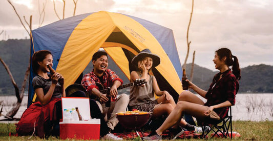 Four people sitting around a campfire with a tent in the background on Masai Mara camping safari game drive experience.