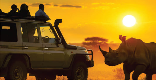 A silhouette of a rhinoceros next to a vehicle with passengers watching, at sunset on night safari game drives in Masai Mara, Kenya.