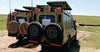 Large two off-road vehicles with spare tires on a dirt road in a grassy area with an open roof on safari in kenya