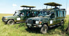 Two green safari vehicles with driver guides and open tops on a grassy field for Amboseli safari vehicle rental Kenya
