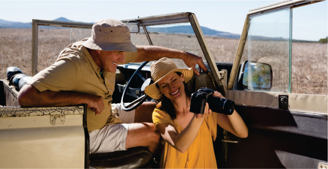 A guide and woman in safari hats sitting in an open safari Samburu National Park tour rental vehicle with a desert landscape in the background