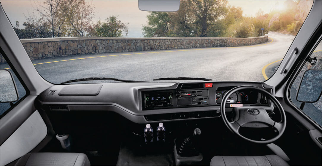 Interior of a bus for rental in Nairobi, Kenya, with dashboard and steering wheel, road visible through windshield.