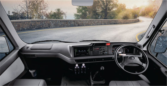 Interior of a bus for rental in Nairobi, Kenya, with dashboard and steering wheel, road visible through windshield.
