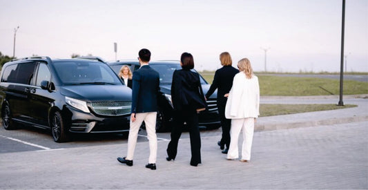 Four people walking towards two black taxis at the Nairobi airport for transfer services