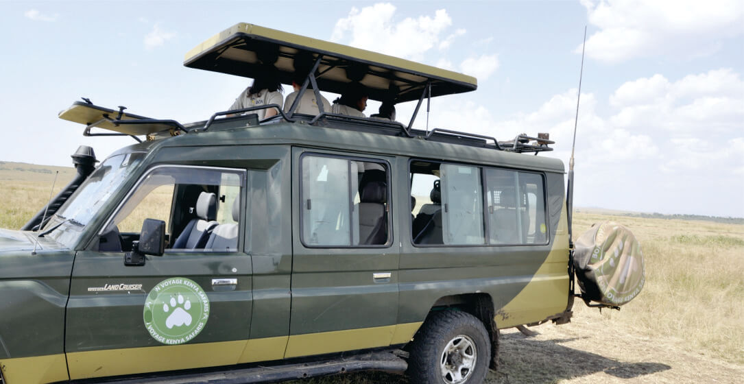green Safari vehicle hire with a green logo, roof tops and passengers on a grassy plain on Ol Pejeta Conservancy safari tours