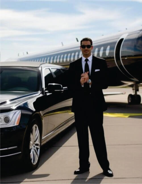 Guide in black suite standing near a black transfer vehicle waiting for guests' arrival at Nairobi Airport