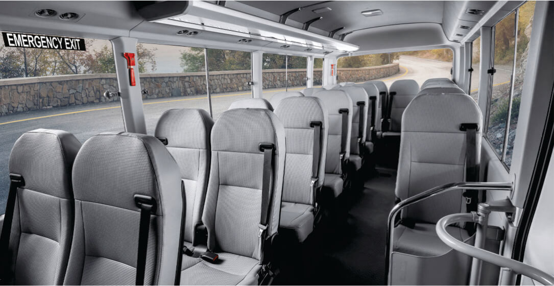 Interior of a bus with rows of seats and emergency exit sign.