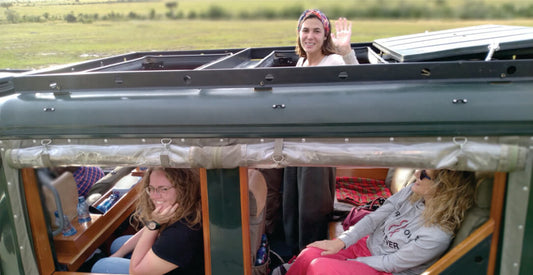 People inside a vehicle with an open roof, waving and sitting on Masai Mara family safari vehicle hire for Kenya