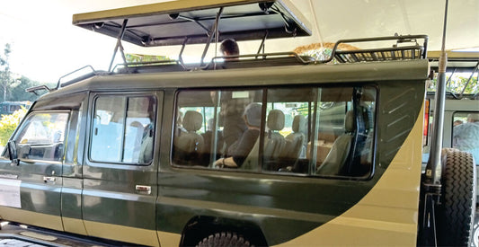 Green safari vehicle with open roof, driver guide and people inside, parked outdoors for rental safari holidays in Kisumu