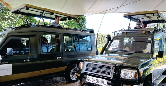 Two green 4x4 Land Cruiser vehicles on rental with open tops and a driver and passengers parked near the hotel in Nairobi