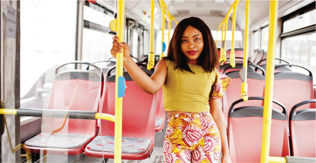 Woman standing on a bus holding onto a yellow handrail